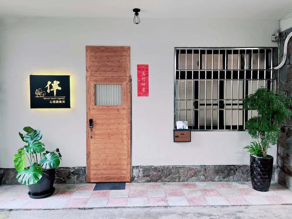 伴心理諮商所入口，木質大門、白牆與兩側綠色盆栽
